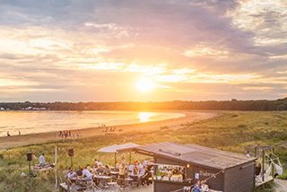 Lillebror vid stranden med gäster i solnedgång